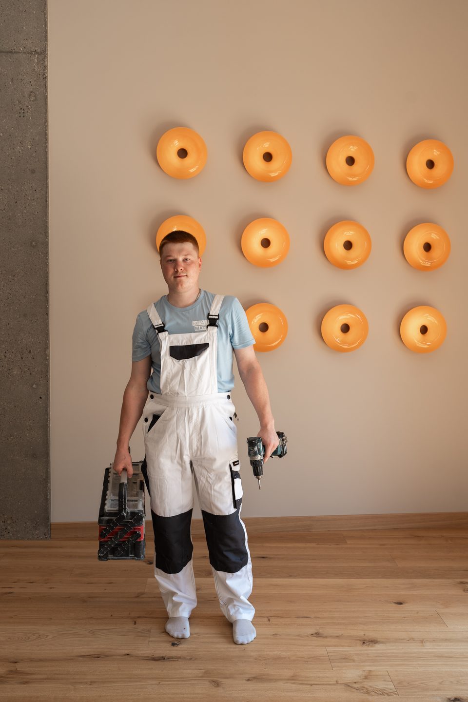 Expat Mates team member in front of a wall of orange lamps